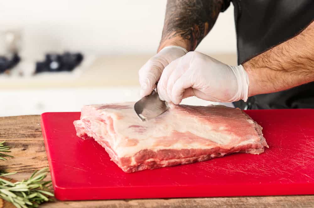 pessoa cortando carne suína